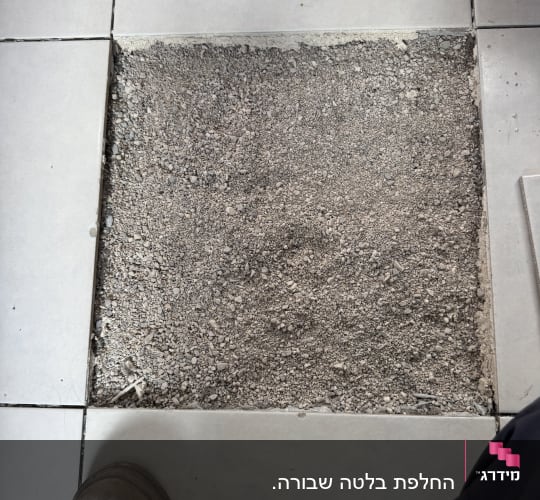 תמונת תקריב של שטח מרצפה שהוסרה במהלך החלפת אריח ריצוף ברצפה